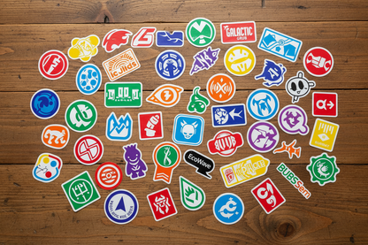 brightly colored stickers with logos, some circular, some square, some oddly shaped, laying on a wooden table
